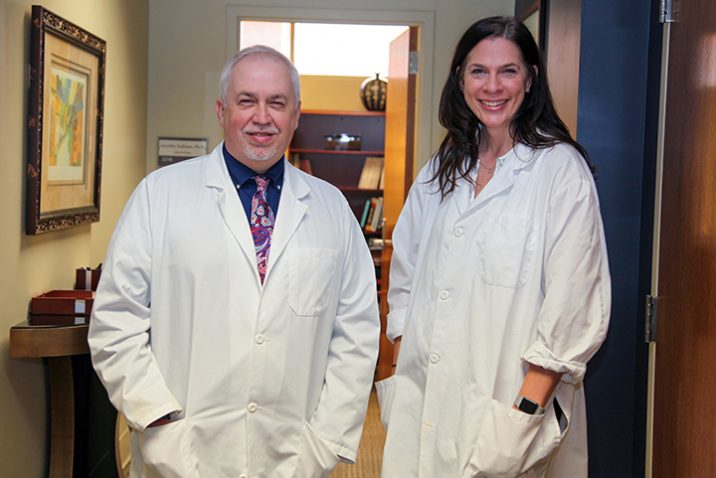 Drs. David Step (on left) and Jennifer Sullivan stand in hallway in white lab coats