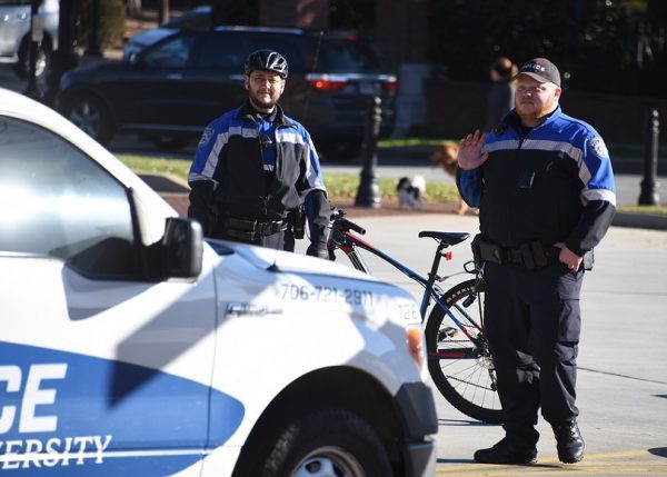 two uniformed officers by police vehicle