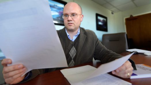 Brian Miller looks at a white paper while sitting at a conference table