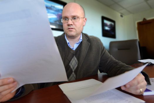 Brian Miller looks at a white paper while sitting at a conference table