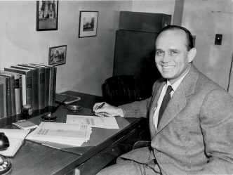 A man sitting down at a desk in a suit.