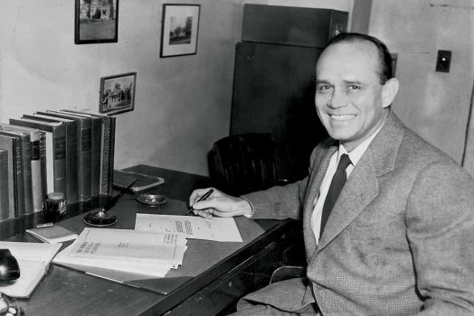 A man sitting down at a desk in a suit.