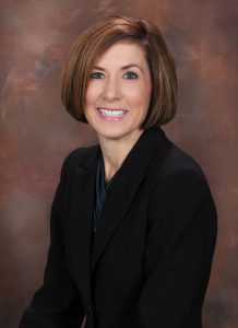 A woman sitting and wearing a suit.