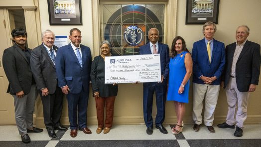 Group stands in front of stained glass window with check