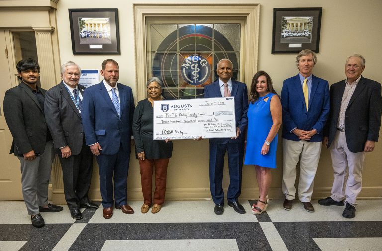 Group stands in front of stained glass window with check