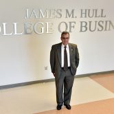 Dean of Hull College standing by sign.