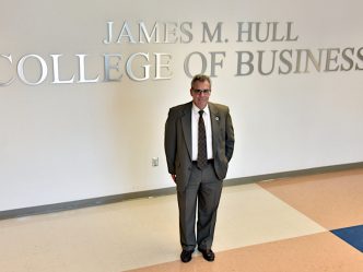 Dean of Hull College standing by sign.