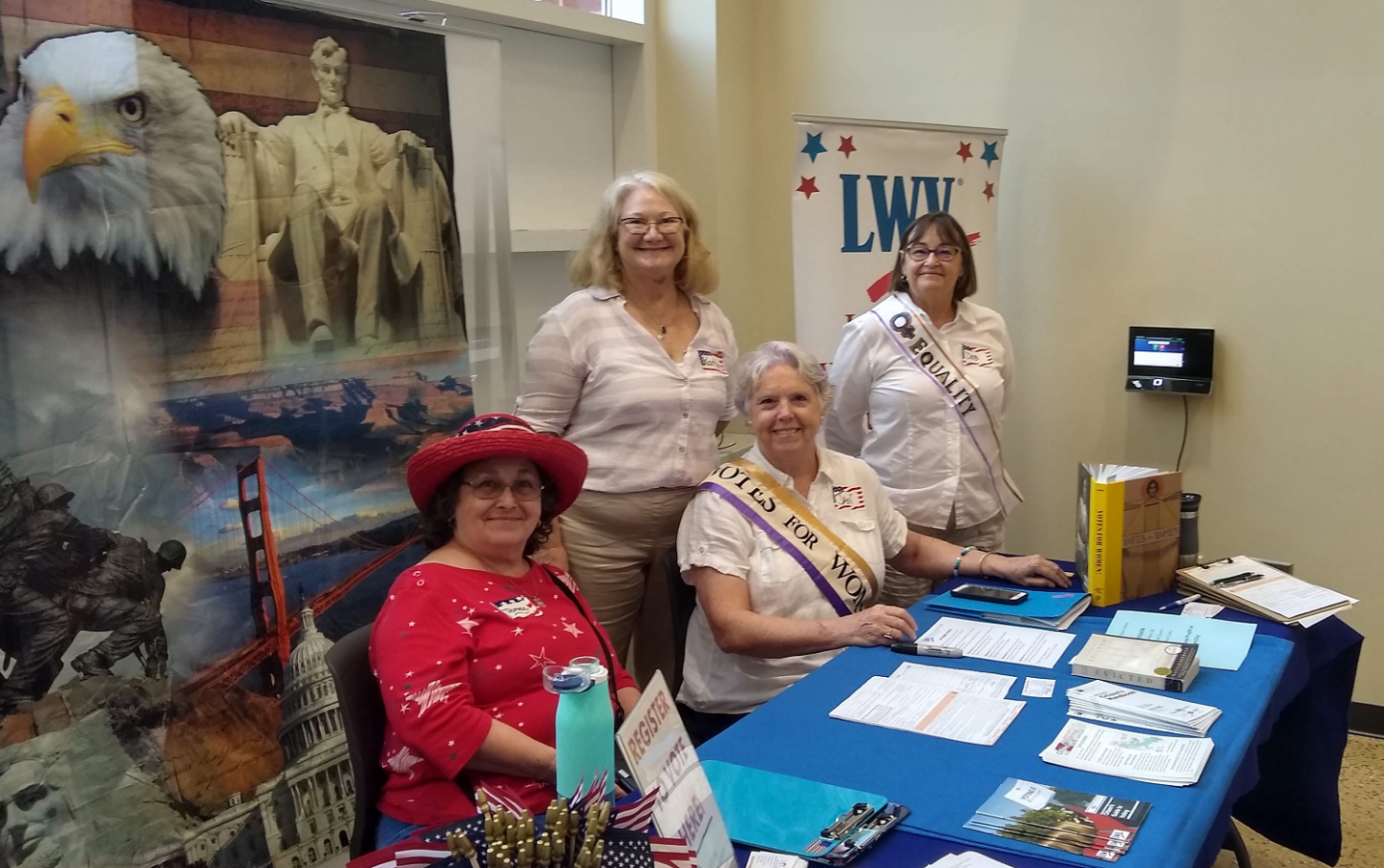 four women smiling behind a table