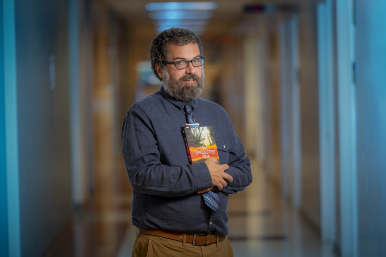 man in blue shirt holding a book