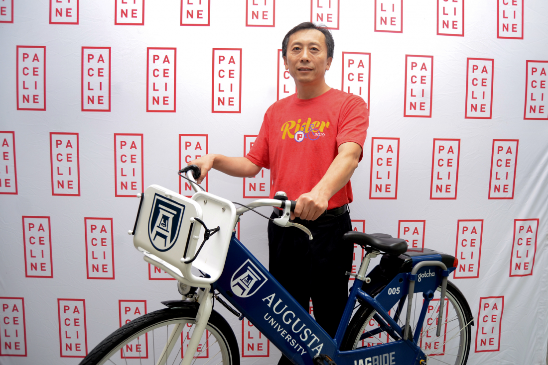a man wearing a red T-shirt holds a blue and white bike