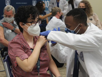 man in white coat administering a vaccine