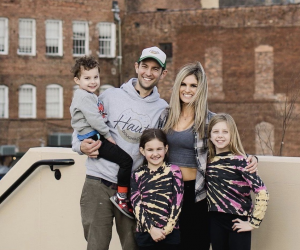 man and woman smiling for photo with 3 kids