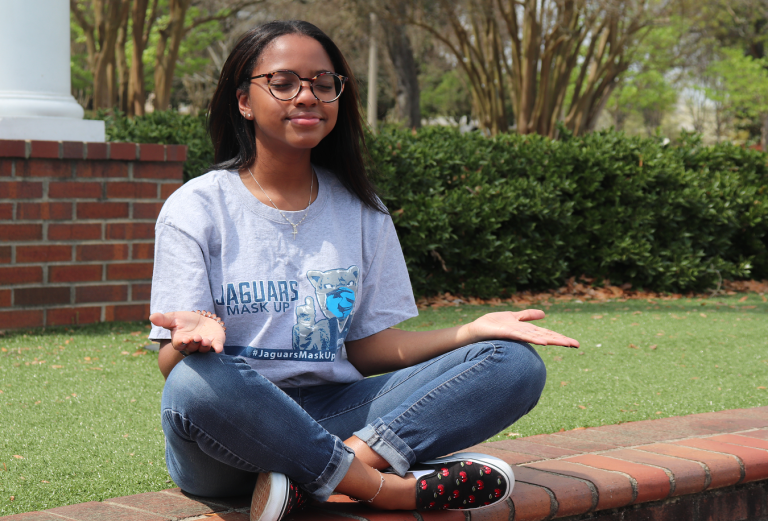 woman wearing glasses meditates outdoors