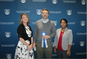 person with award ribbon accompanied by two others