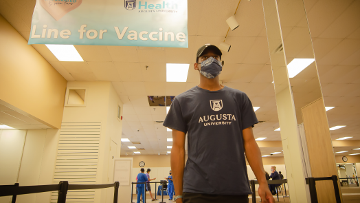 male student walking up to get his COVID-19 vaccine