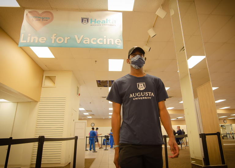 male student walking up to get his COVID-19 vaccine
