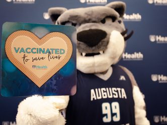 Mascot with sign: Vaccinated to Save Lives