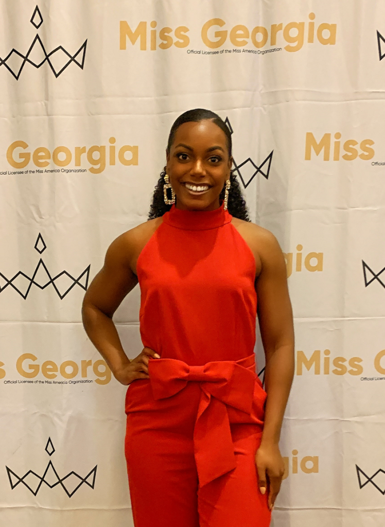 woman wearing red romper in front of "Miss Georgia" backdrop