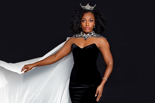 woman wearing black dress, white cape and crown