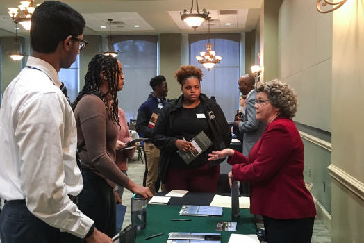 3 people speaking to a woman across a table
