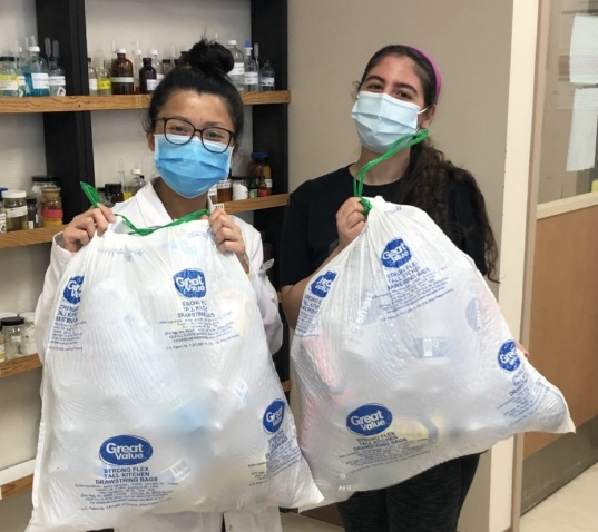two women holding trash bags