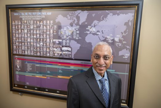 Man stands in front of poster smiling