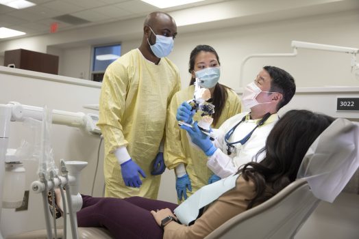 male dental professor demonstrating to two students