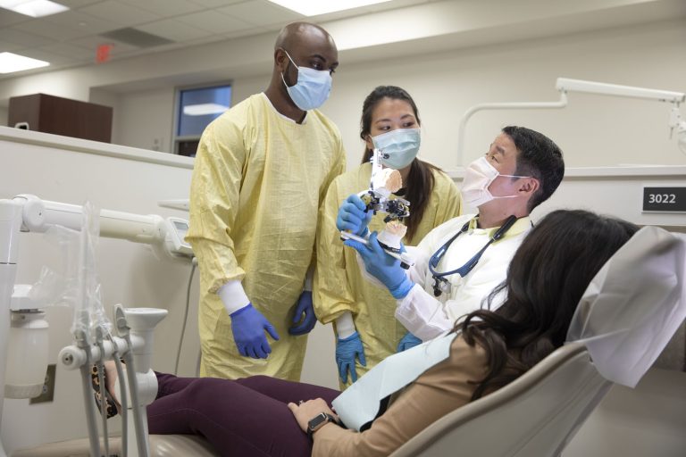 male dental professor demonstrating to two students