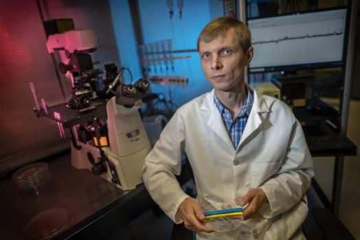 Man in white coat sits in lab