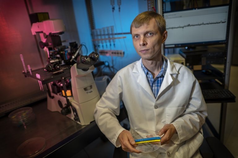 Man in white coat sits in lab