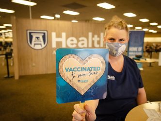 Nurse holding "vaccinated to save lives" sign