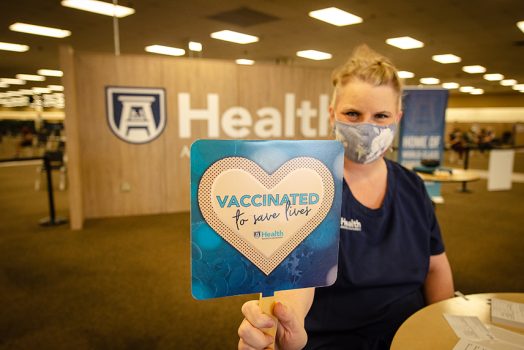 Nurse holding "vaccinated to save lives" sign