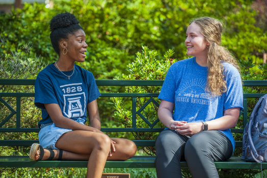 two women sitting on a bench, talking