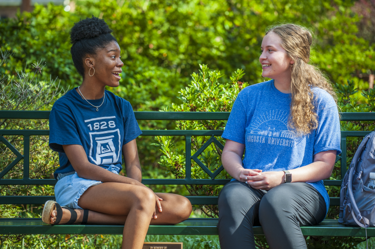 two women sitting on a bench, talking