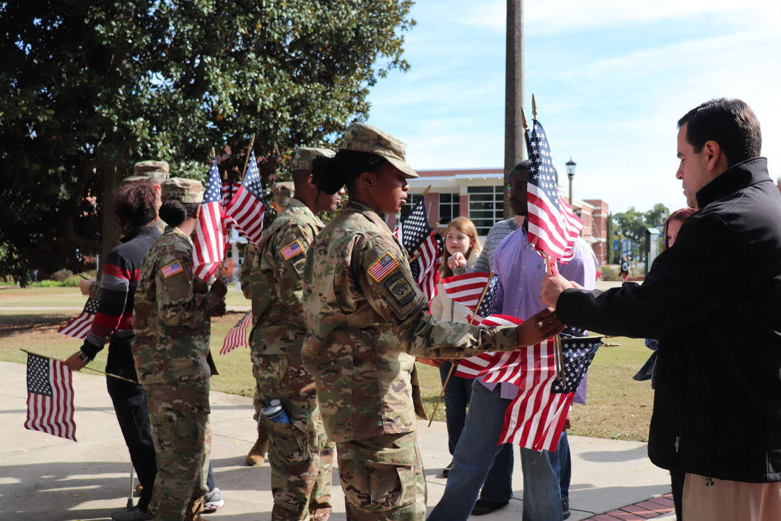 a woman in uniform handing a man a flag