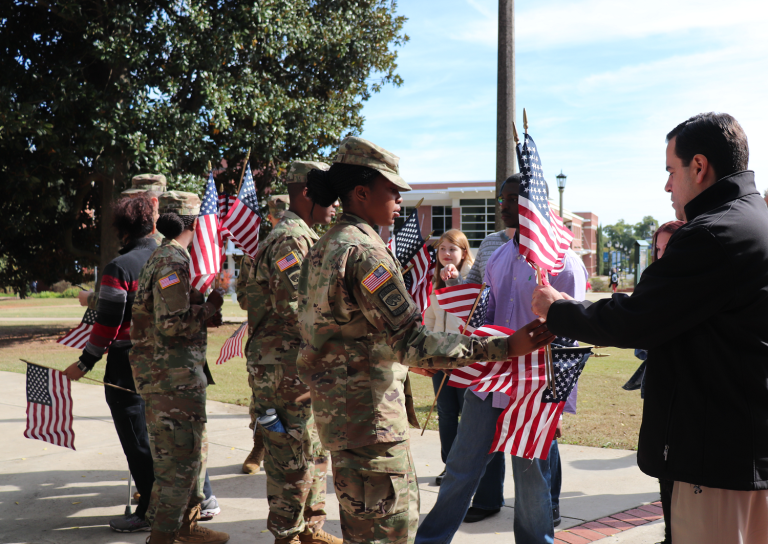 a woman in uniform handing a man a flag