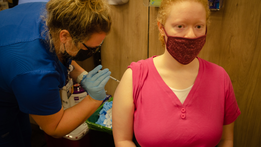 woman administers a vaccine to a student