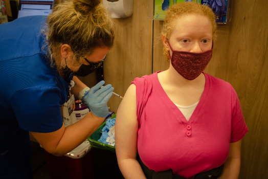 woman administers a vaccine to a student