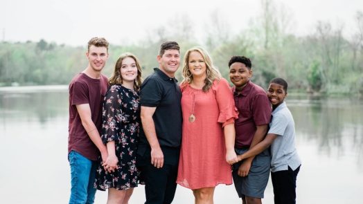 family standing in front of body of water