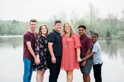 family standing in front of body of water