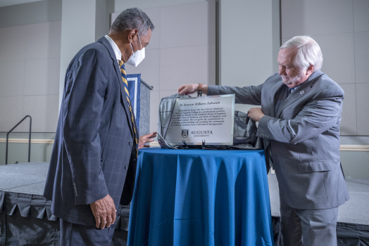 two men shown beside a plaque