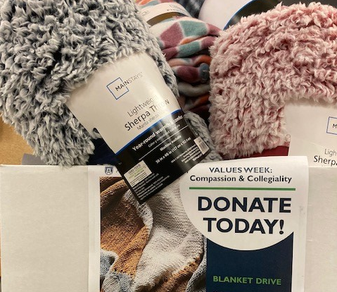 donated blankets beside a book drive poster
