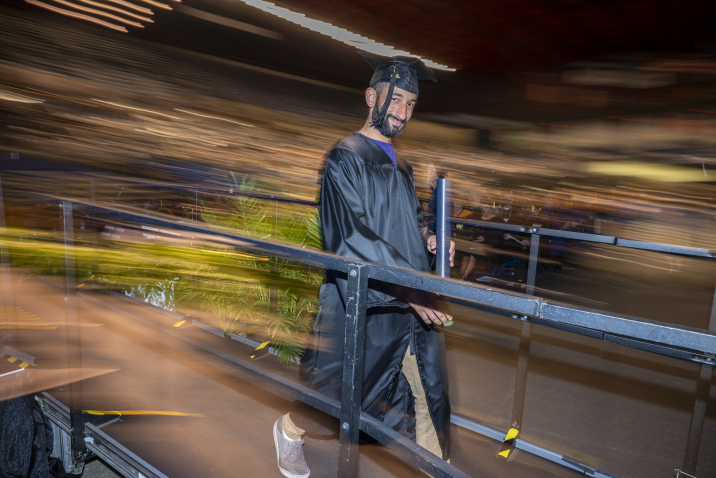 man leaving stage with degree in hand