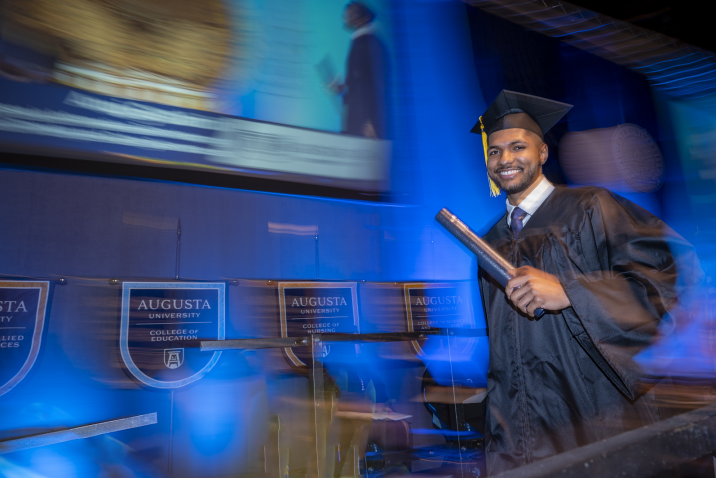 man leaving stage with degree in hand