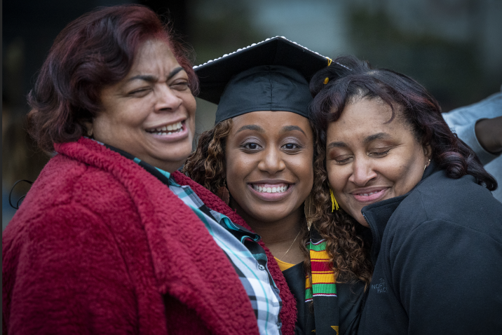 graduate smiling beside 2 women