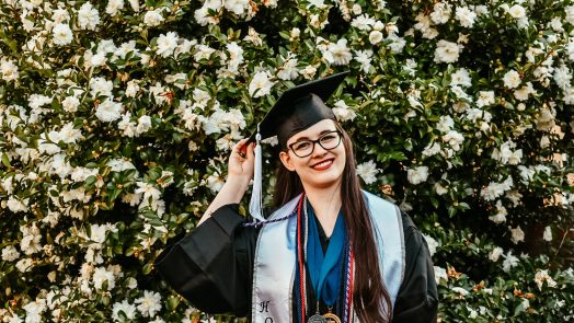 woman smiling in front of bush with flowers