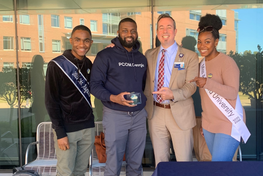 the Augusta University provost standing with 3 students