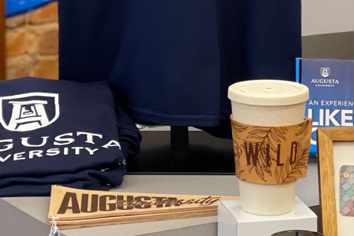 a leather pennant and leather cup sleeve next to other AU merchandise