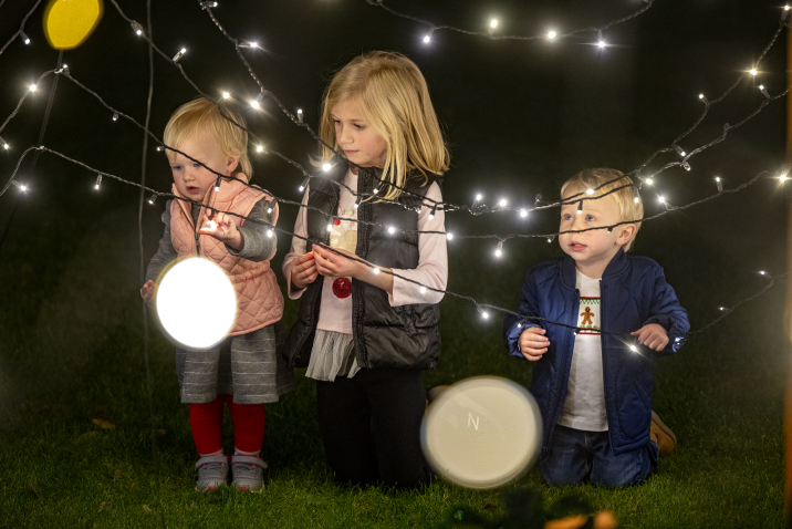 3 children looking at string lights