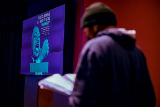 man reading, picture of Martin Luther King Jr. in the distance